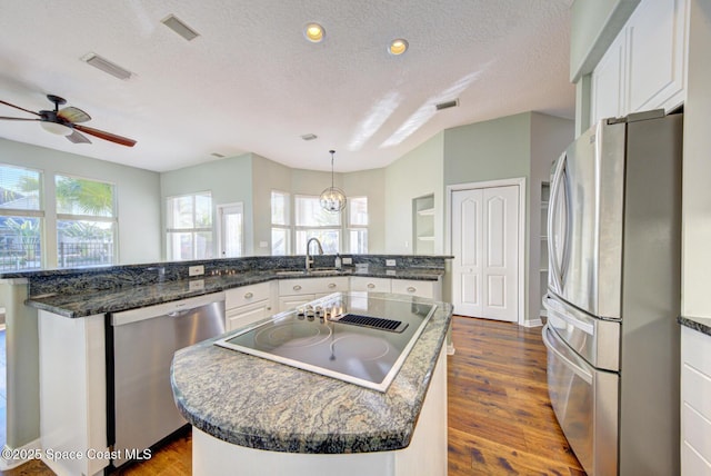 kitchen featuring a kitchen island, white cabinetry, a textured ceiling, and appliances with stainless steel finishes