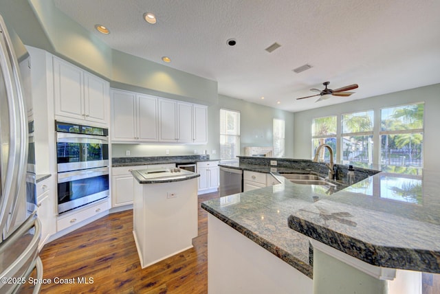 kitchen featuring white cabinetry, a large island, sink, ceiling fan, and stainless steel appliances