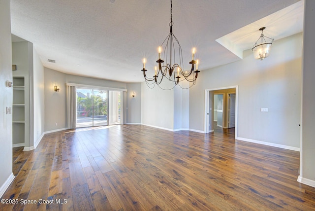 spare room with a textured ceiling, dark hardwood / wood-style floors, and a notable chandelier