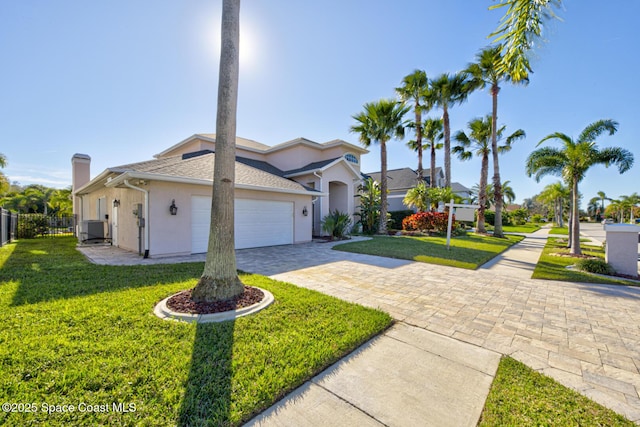 view of front of property with a garage, a front yard, and central AC