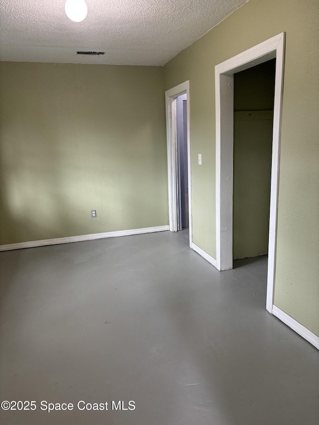 unfurnished room featuring a textured ceiling and concrete floors