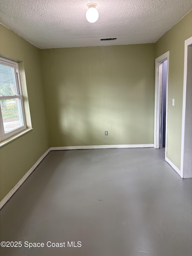 unfurnished room featuring a textured ceiling and concrete floors