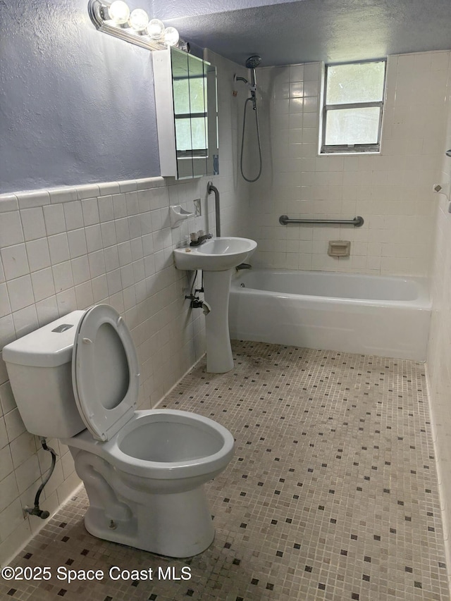 bathroom with tile patterned floors, toilet, tile walls, and a wealth of natural light