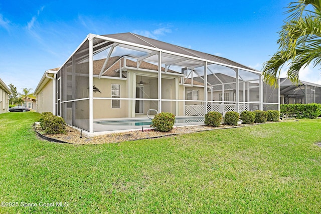 rear view of house featuring ceiling fan and a lawn