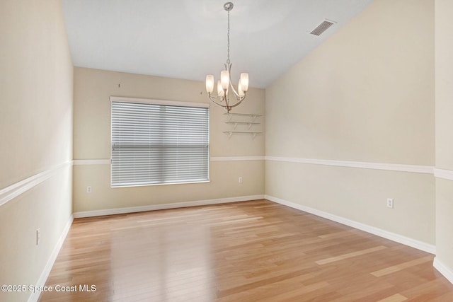 empty room with a chandelier and light wood-type flooring