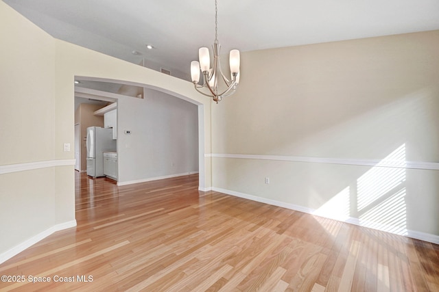 spare room with an inviting chandelier and wood-type flooring