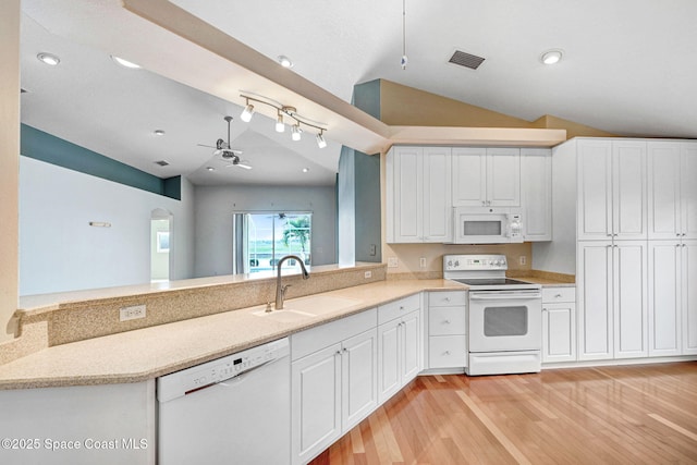 kitchen with lofted ceiling, sink, white cabinets, kitchen peninsula, and white appliances