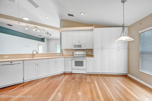 kitchen featuring lofted ceiling, sink, white cabinetry, decorative light fixtures, and white appliances