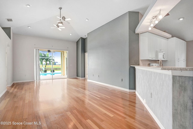 unfurnished living room with high vaulted ceiling, ceiling fan, and light wood-type flooring