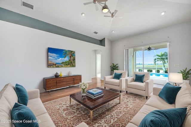 living room featuring lofted ceiling, ceiling fan, and light hardwood / wood-style flooring