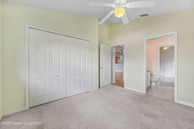 unfurnished bedroom featuring ensuite bath, ceiling fan, vaulted ceiling, light colored carpet, and a closet