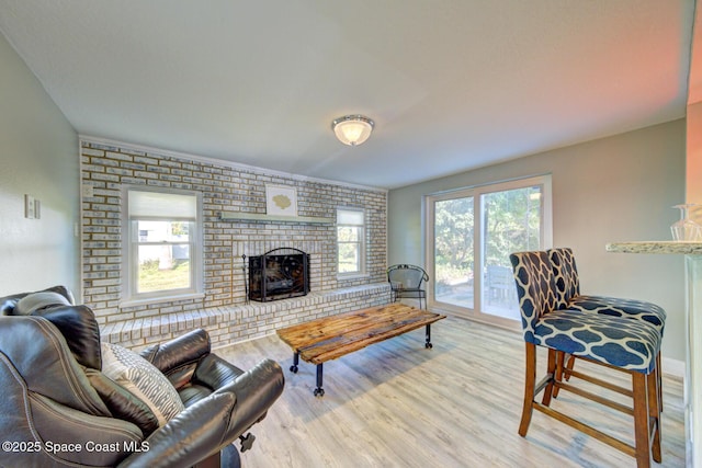 living room featuring light wood-type flooring, a brick fireplace, and brick wall