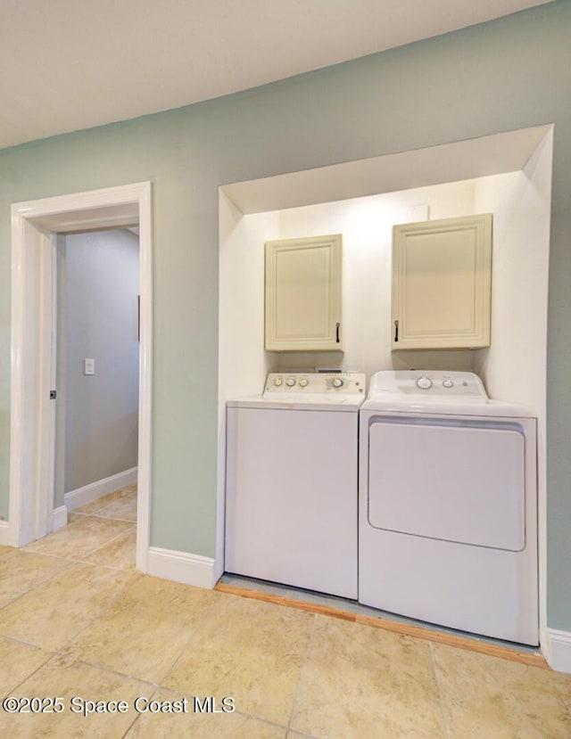 clothes washing area featuring washing machine and clothes dryer and cabinets