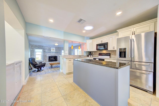 kitchen with high end refrigerator, white cabinetry, washer and clothes dryer, and electric stove