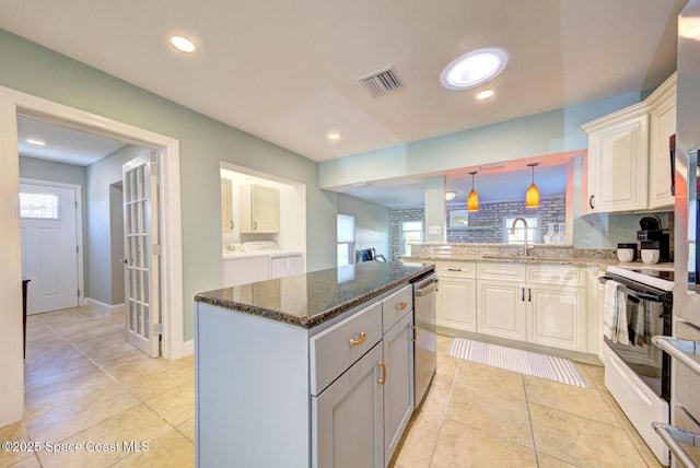 kitchen with washer and clothes dryer, dishwasher, a center island, white electric range oven, and white cabinetry