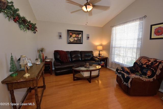 living room with ceiling fan, light hardwood / wood-style floors, and lofted ceiling