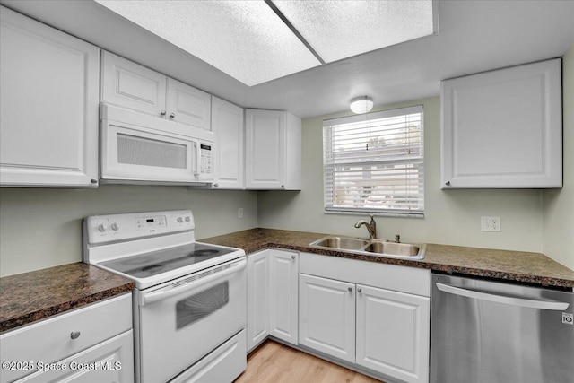 kitchen with white cabinetry, sink, white appliances, and light wood-type flooring