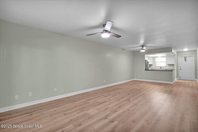 spare room with a textured ceiling, light hardwood / wood-style flooring, and ceiling fan