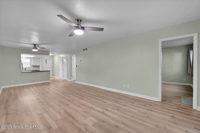 unfurnished living room featuring ceiling fan, light wood-type flooring, and a textured ceiling