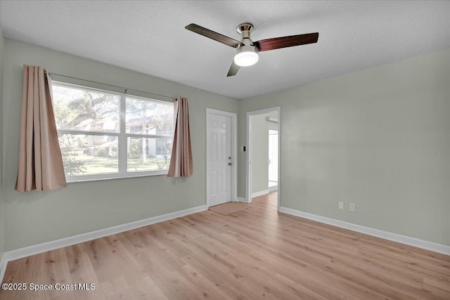 empty room with ceiling fan, light hardwood / wood-style flooring, and a textured ceiling