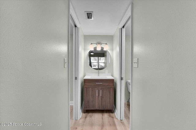 hallway with sink and light hardwood / wood-style flooring