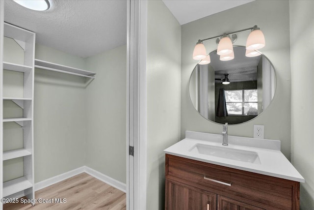 bathroom with hardwood / wood-style floors, vanity, a textured ceiling, and ceiling fan