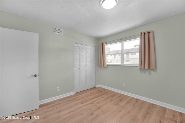 unfurnished bedroom featuring light hardwood / wood-style floors, a textured ceiling, and a closet