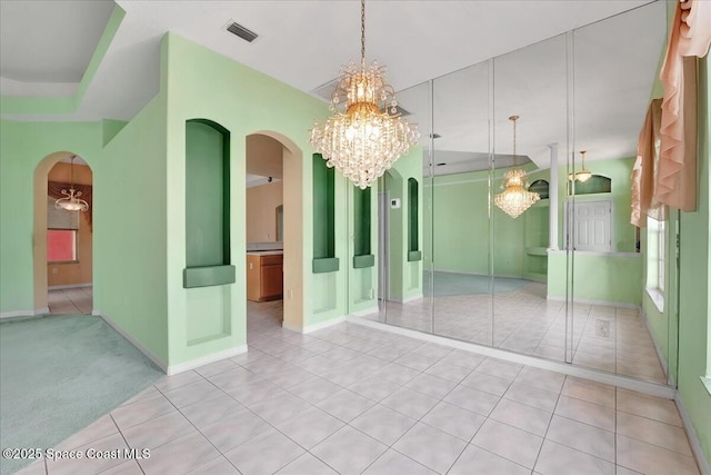 empty room featuring light tile patterned floors and an inviting chandelier