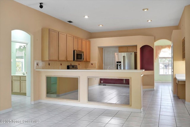 kitchen featuring tasteful backsplash, light brown cabinets, light tile patterned flooring, and appliances with stainless steel finishes