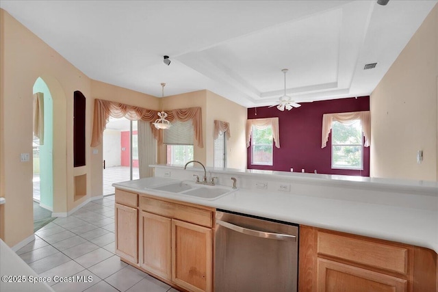 kitchen with stainless steel dishwasher, ceiling fan with notable chandelier, a tray ceiling, sink, and light tile patterned floors