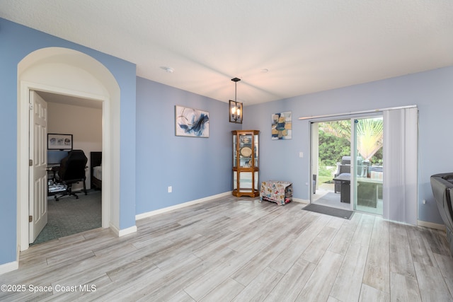 empty room with light wood-type flooring and an inviting chandelier