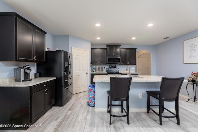 kitchen with stainless steel appliances, a kitchen island with sink, light hardwood / wood-style floors, and sink