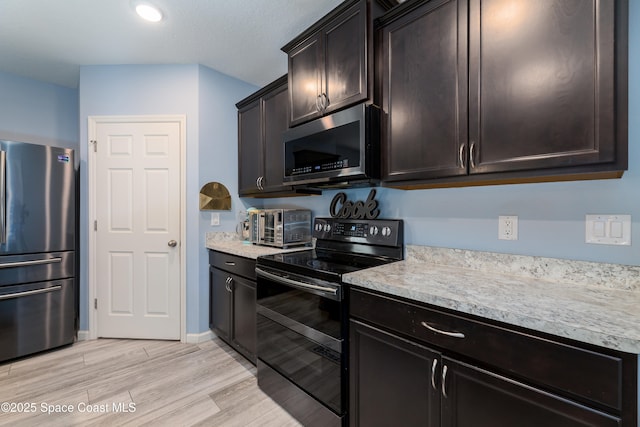 kitchen with dark brown cabinetry, stainless steel appliances, and light hardwood / wood-style floors