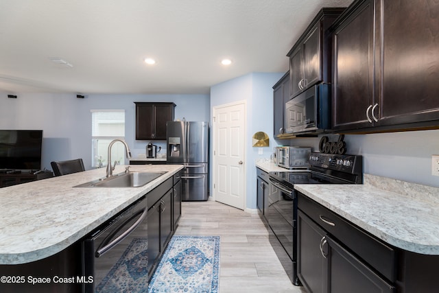 kitchen featuring appliances with stainless steel finishes, a center island with sink, dark brown cabinets, and sink