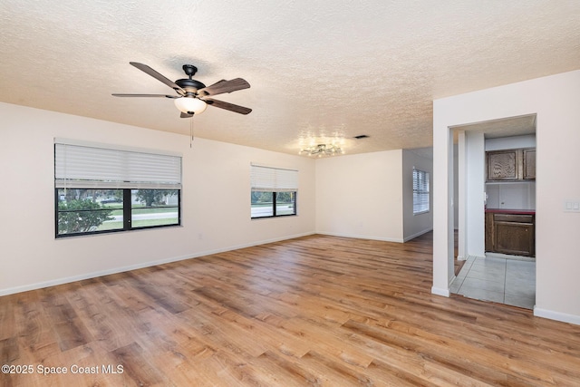 spare room with a textured ceiling, light wood-type flooring, and ceiling fan