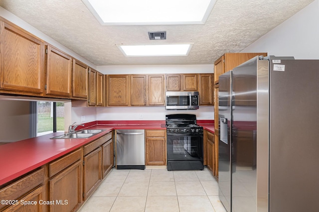 kitchen with a textured ceiling, light tile patterned floors, sink, and appliances with stainless steel finishes