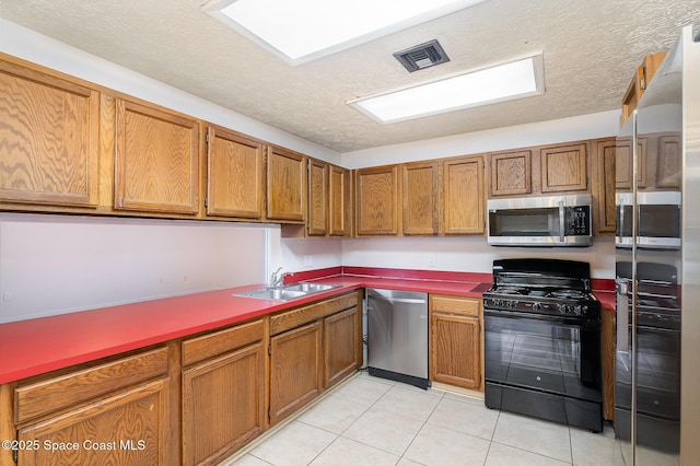 kitchen featuring a textured ceiling, sink, light tile patterned floors, and stainless steel appliances