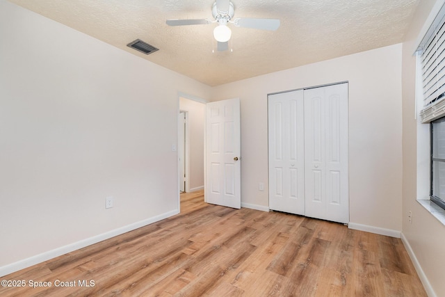 unfurnished bedroom with ceiling fan, light hardwood / wood-style floors, a textured ceiling, and a closet