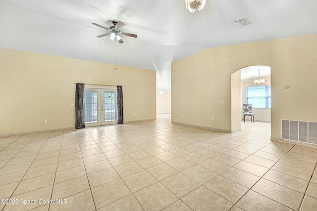 spare room with light tile patterned floors, ceiling fan with notable chandelier, french doors, and a healthy amount of sunlight