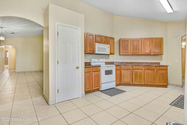 kitchen with pendant lighting, white appliances, a high ceiling, and light tile patterned floors