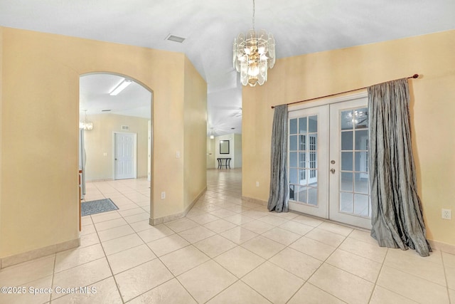 tiled spare room featuring french doors and an inviting chandelier