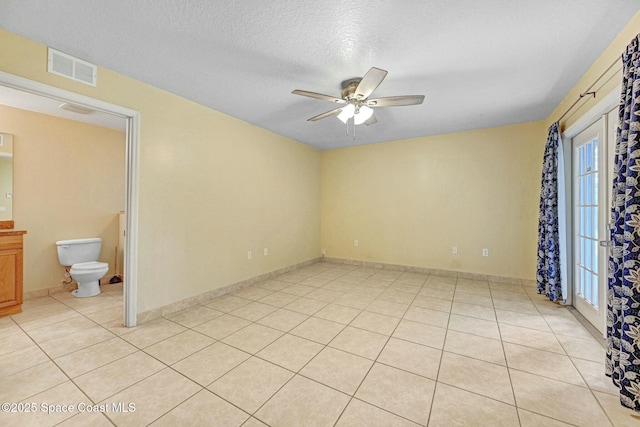 tiled empty room with ceiling fan and a textured ceiling