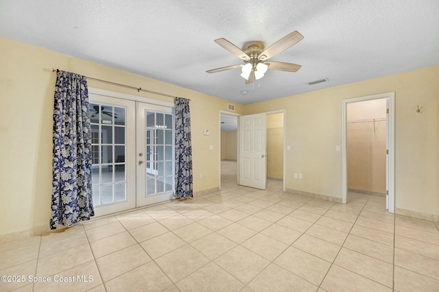 empty room with ceiling fan, light tile patterned floors, a textured ceiling, and french doors