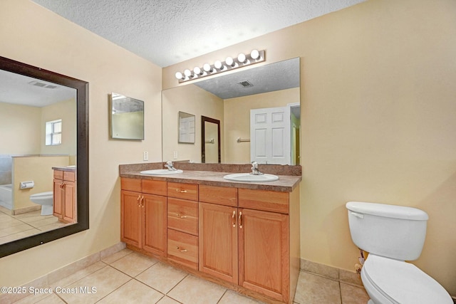 bathroom with tile patterned floors, vanity, a textured ceiling, and toilet