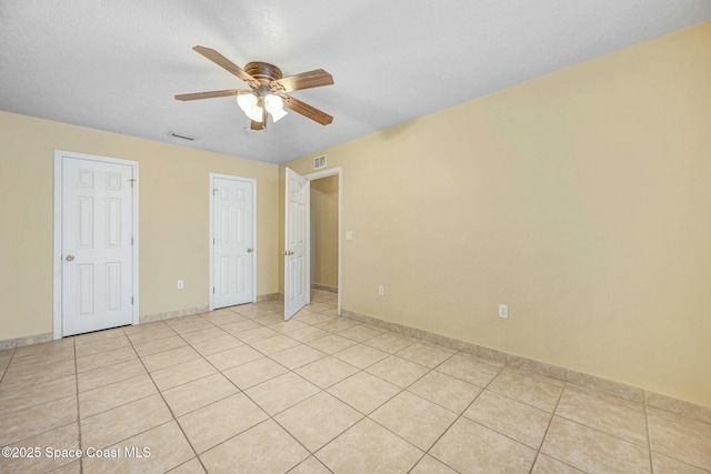 unfurnished bedroom featuring ceiling fan, light tile patterned flooring, and a textured ceiling