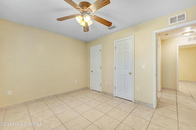 unfurnished bedroom featuring light tile patterned floors, a textured ceiling, and ceiling fan