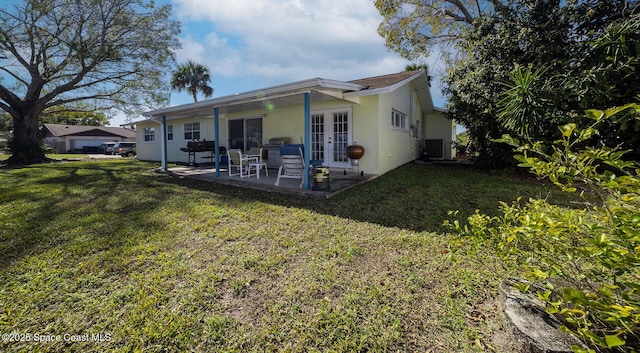 back of property with french doors, cooling unit, a patio area, and a lawn