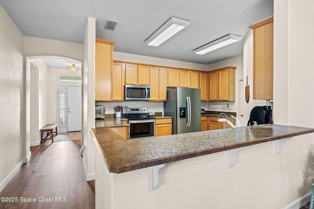 kitchen featuring stainless steel appliances, light wood-type flooring, a breakfast bar area, and kitchen peninsula