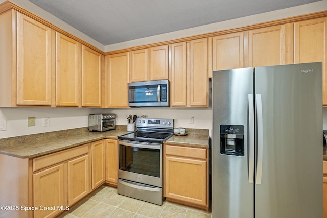 kitchen featuring appliances with stainless steel finishes, light tile patterned floors, and light brown cabinets