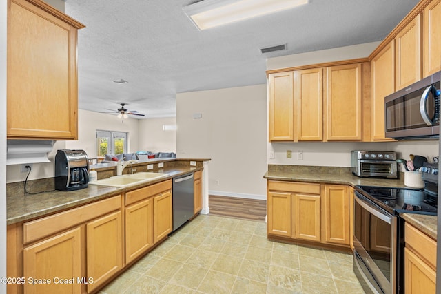 kitchen featuring ceiling fan, stainless steel appliances, sink, and a textured ceiling